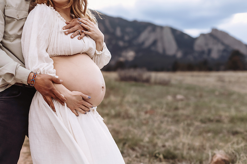 Casual maternity photoshoot featuring a pregnant woman in jeans and a cozy cardigan, capturing natural moments outdoors