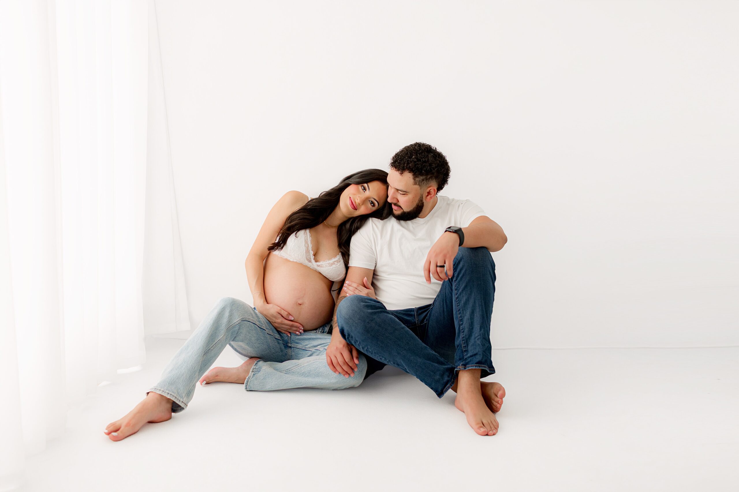 modern maternity photoshoot in white studio | couple holding baby bump