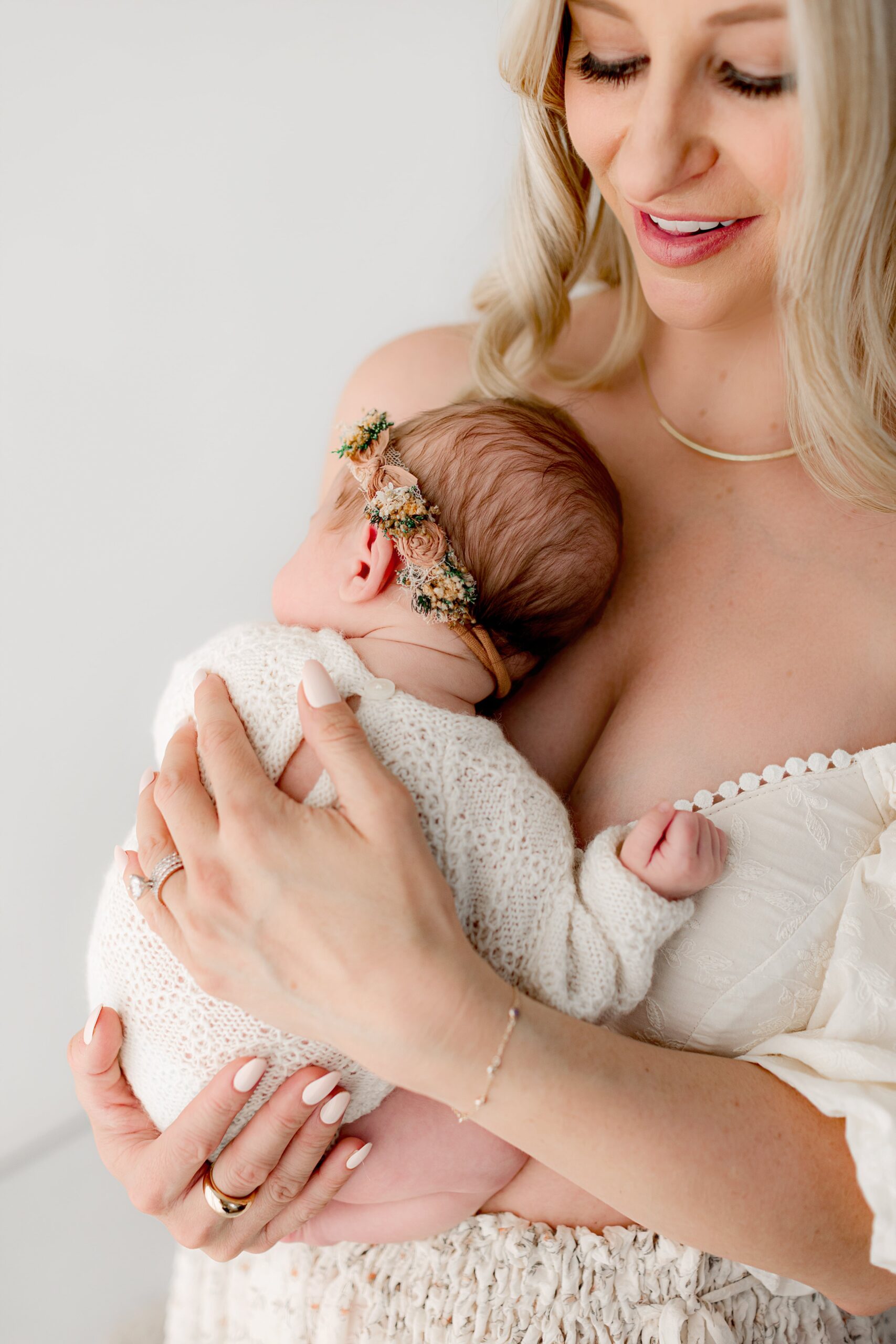 new mom holds her baby girl in fort collins photography studio during her newborn photo session.
