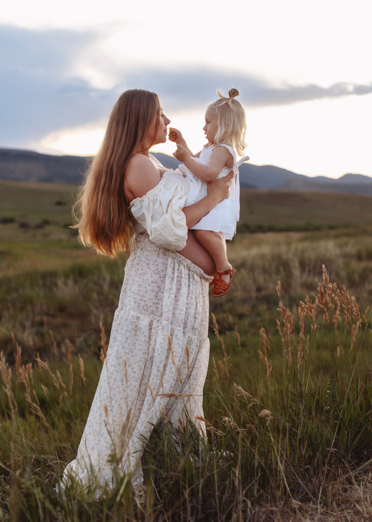 Big brother hugging mom’s bump during family maternity session outdoors in Northern Colorado
