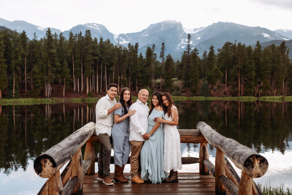  Family standing together in front of mountain views during a golden hour session in Estes Park, Colorado.