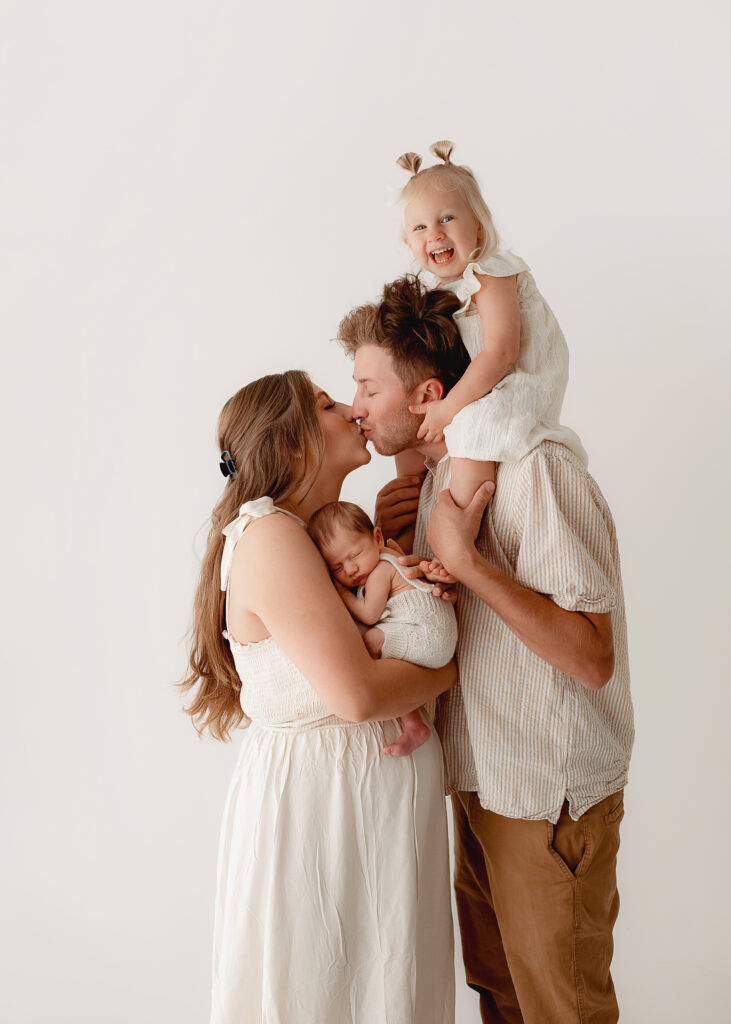 parents holding their newborn baby wearing neutral outfits for a newborn photo session