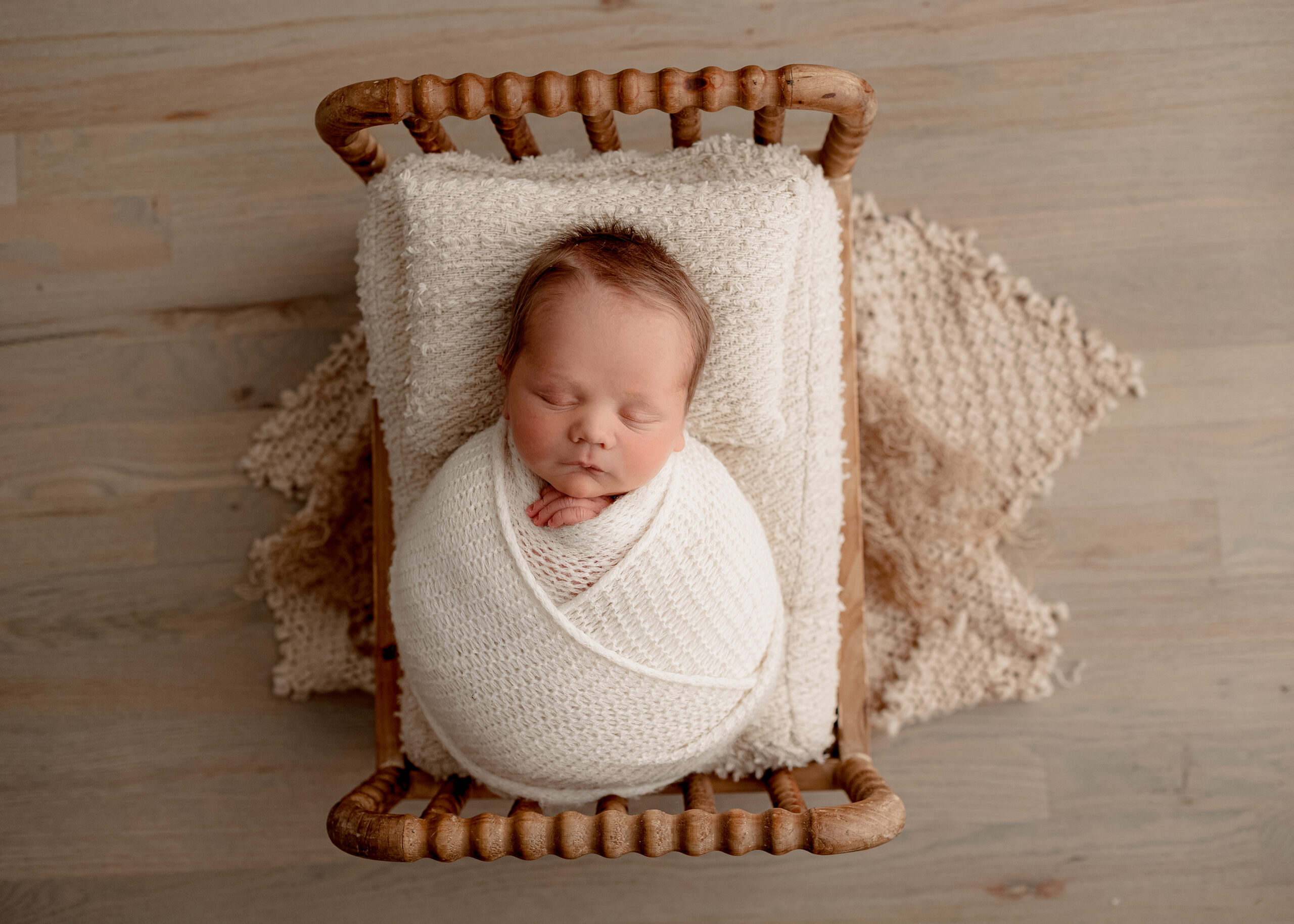 sleepy newborn baby posed on neutral bed setup during studio newborn photography session