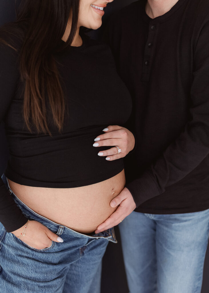 couple with hands on baby bump during modern denver studio photoshoot