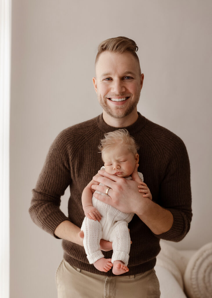Denver newborn photographer father holding newborn baby natural studio light